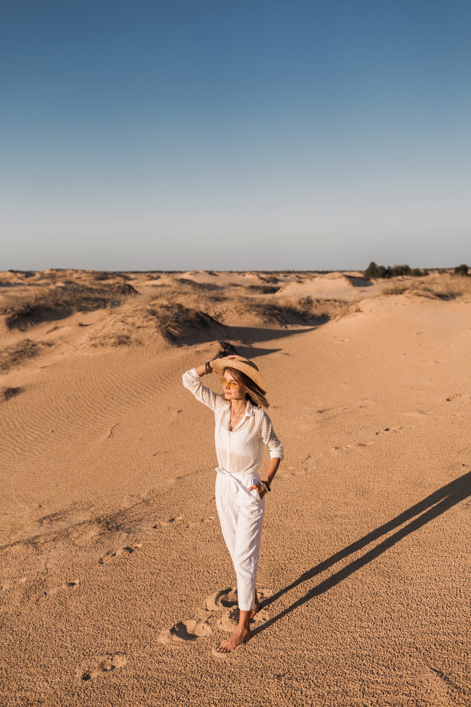 stylish beautiful woman walking desert sand white outfit wearing straw hat sunset 2 scaled