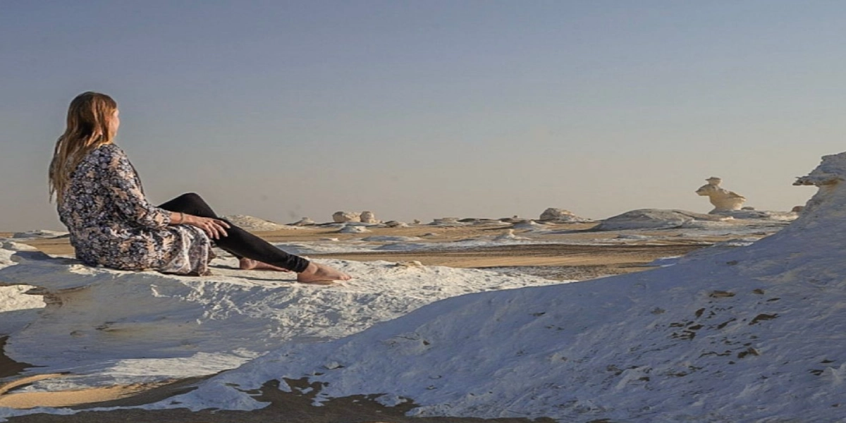 Panoramic landscape of Egypt’s White and Black Deserts with travelers exploring chalk formations and volcanic hills during a Heart Egypt Tours adventure.