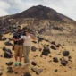 Tourists exploring the Black Desert in Egypt with Heart Egypt Tours, surrounded by black volcanic hills and golden sand dunes at sunset.