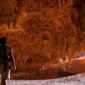 Travelers exploring Qara Cave in Fayoum, Egypt, surrounded by dramatic rock formations and soft desert light filtering through the cave entrance.