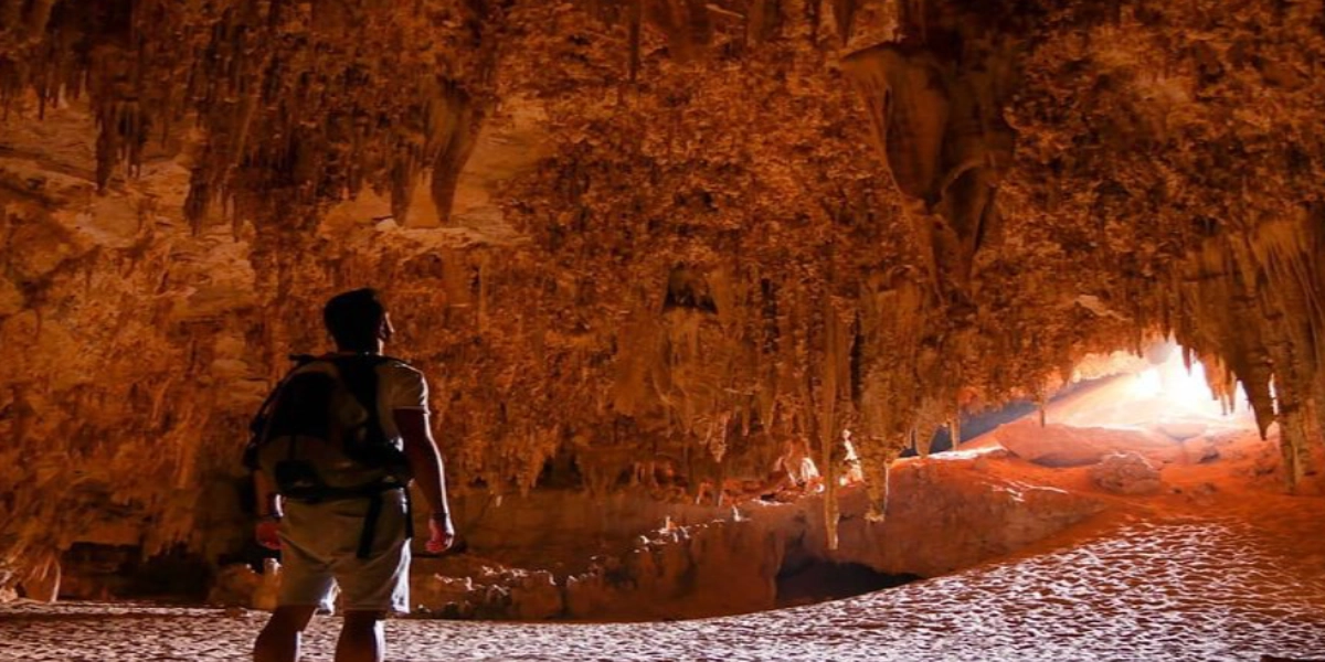 Travelers exploring Qara Cave in Fayoum, Egypt, surrounded by dramatic rock formations and soft desert light filtering through the cave entrance.