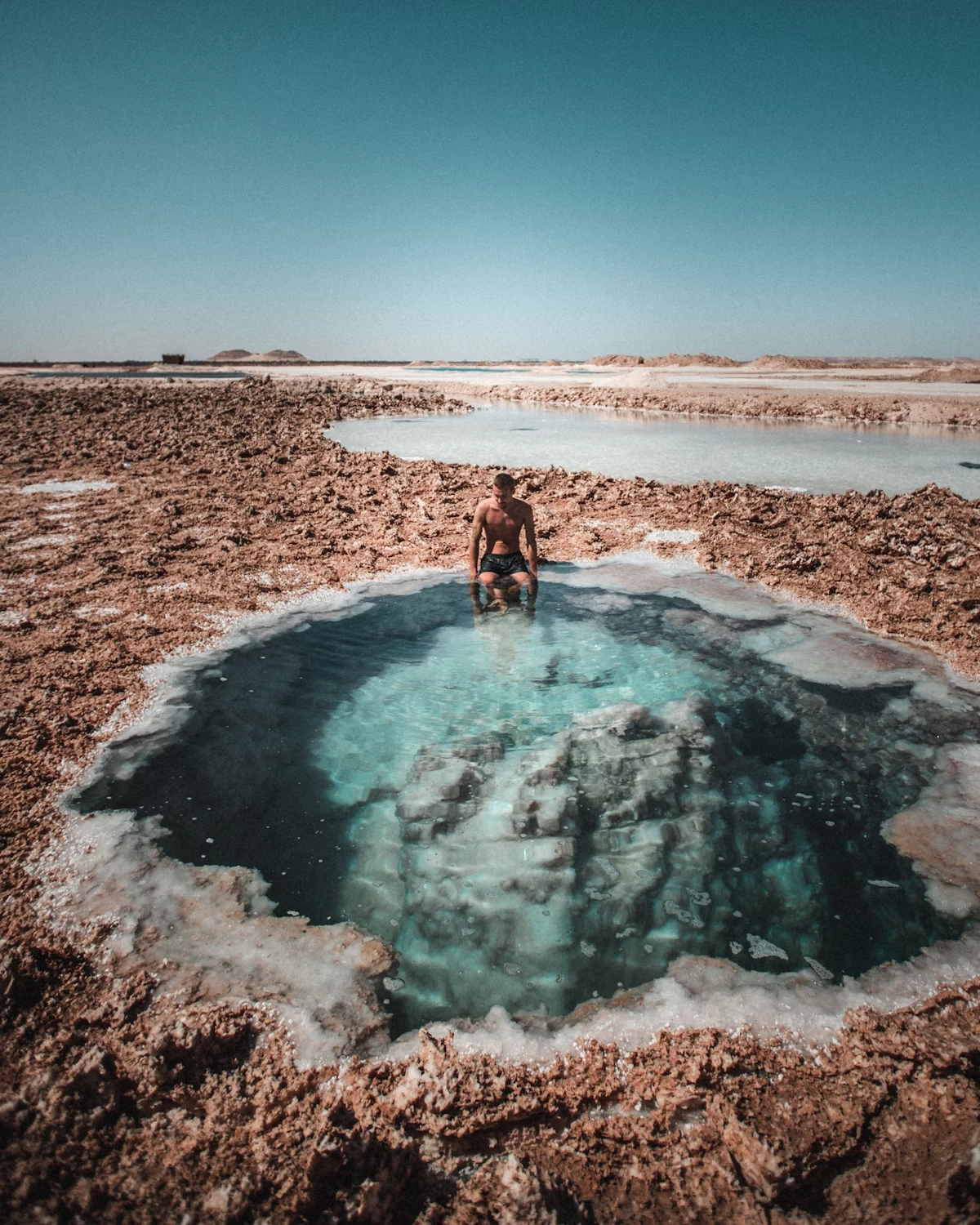 Sunset over Siwa Oasis showing palm groves, salt flats, and desert landscape, with travelers exploring and relaxing on a Heart Egypt Tours adventure.