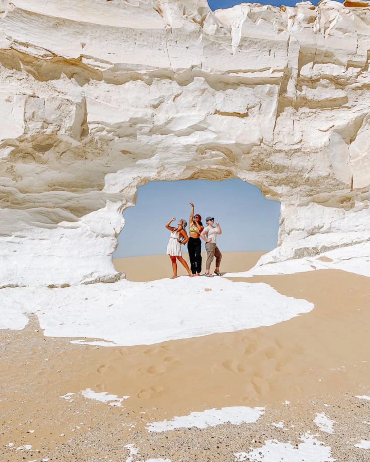 Desert campsite with tents, sleeping bags, and campfire at sunset in Egypt’s White Desert, prepared for a Heart Egypt Tours adventure.