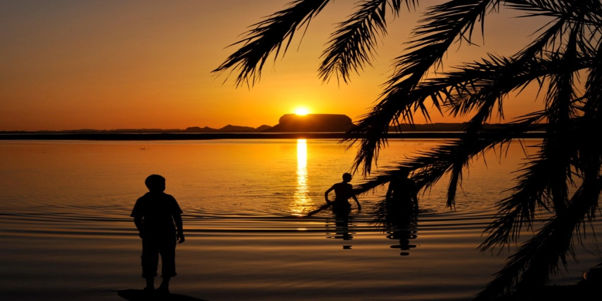 Golden sunset over Fatnas Island in Siwa Oasis and volcanic hills of Bahariya’s Black Desert, seen during a Heart Egypt Tours desert journey.